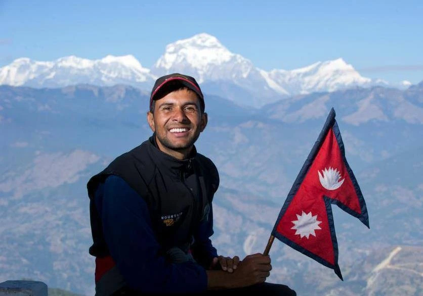 man hosding nepal flag at poon hill